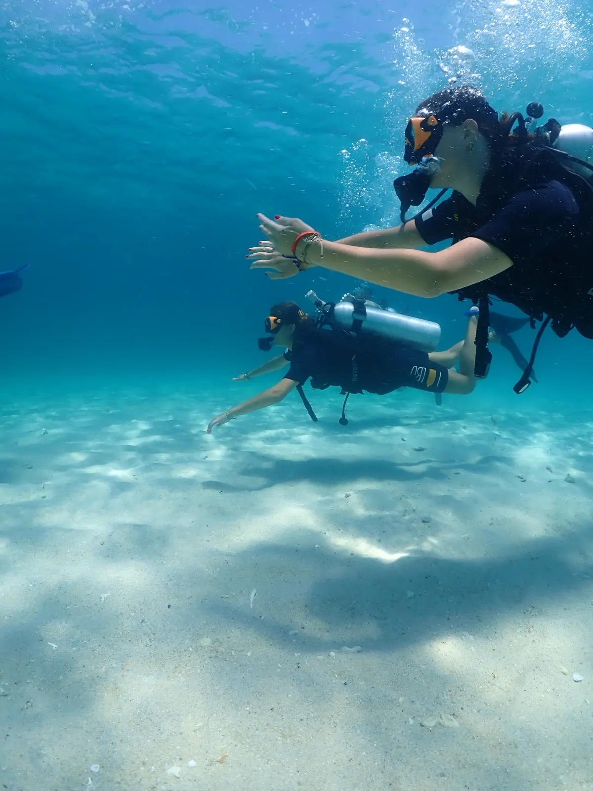 Open Water student guided by an instructor over the sand in Koh Lipe