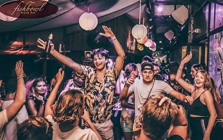 A packed party crowd dancing with their arms in the air under paper lanterns at Fishbowl Beach Bar
