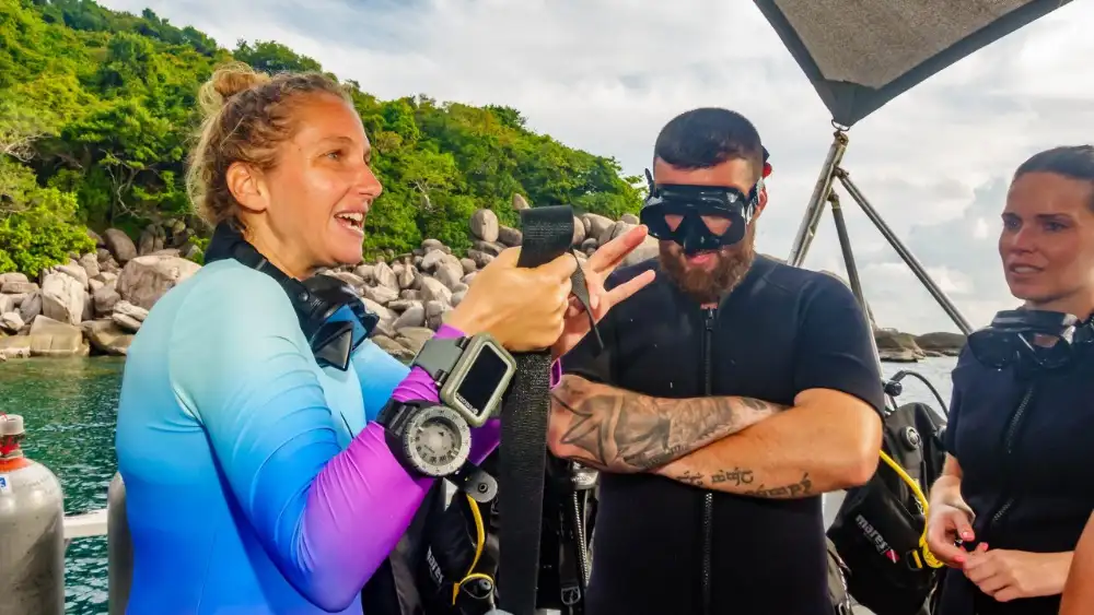 A woman in divemaster training on Koh Tao kitted up in scuba gear at the water's edge
