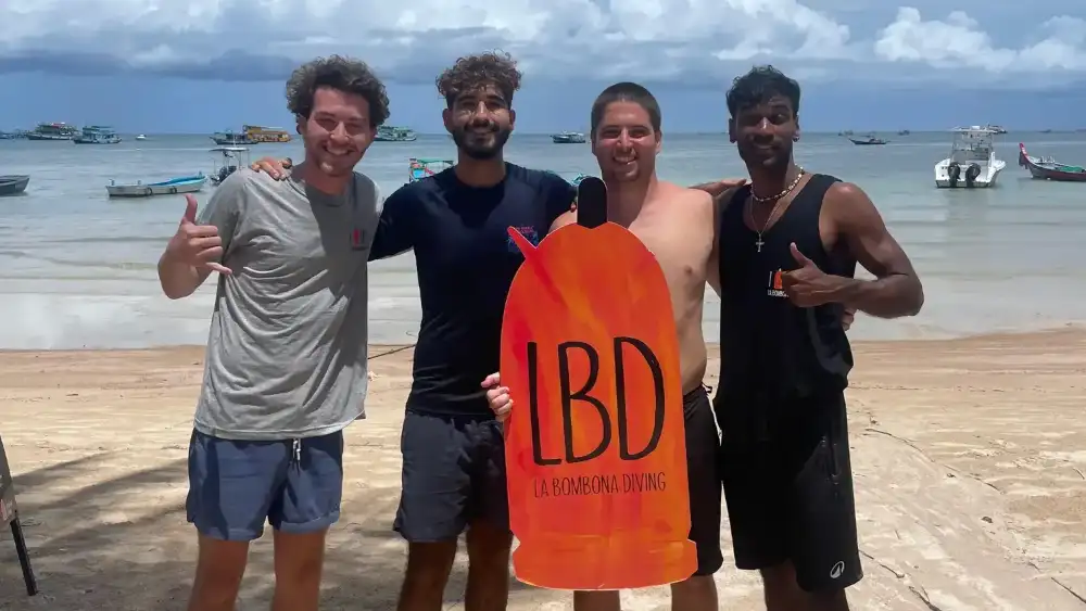 A group of happy divers posing together on the boat after a dive in Koh Tao, Thailand
