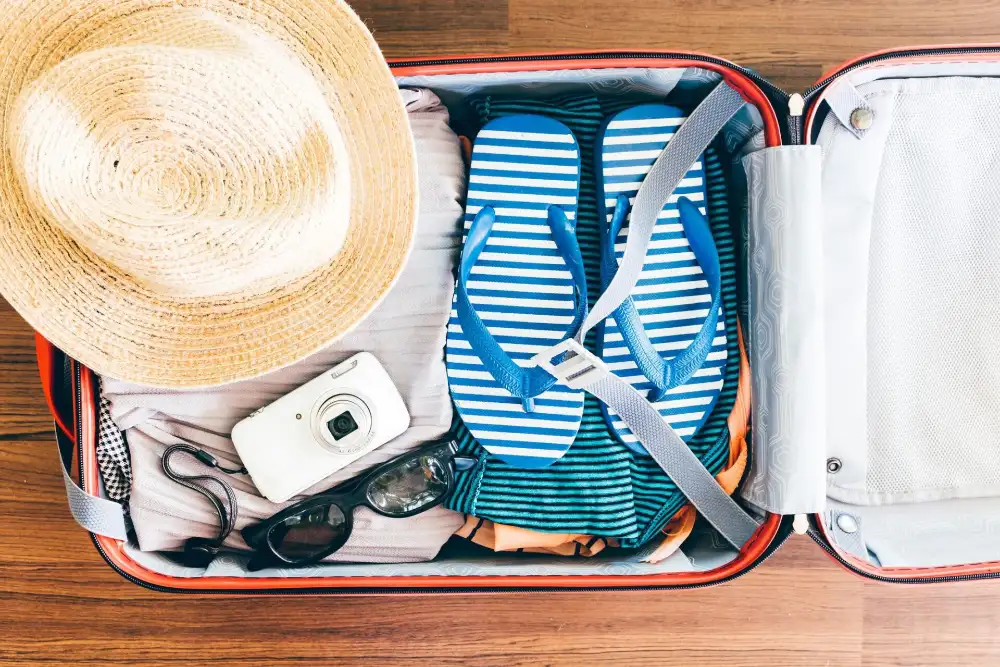 A traveller packing light clothes and essentials into a small backpack for an island-hopping trip