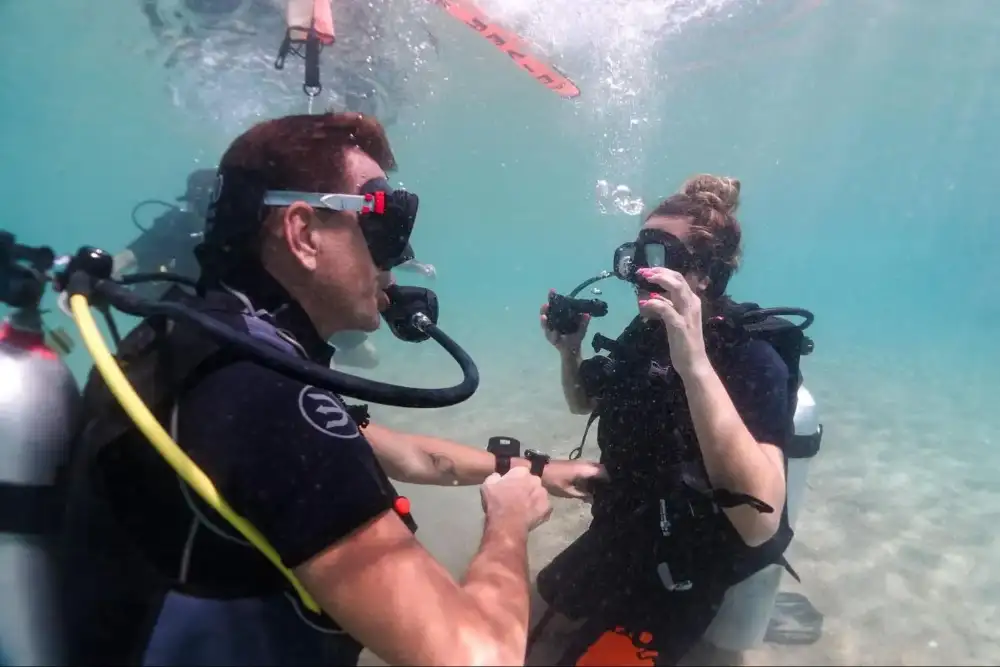 Beginner scuba divers practising skills underwater in shallow water with an instructor