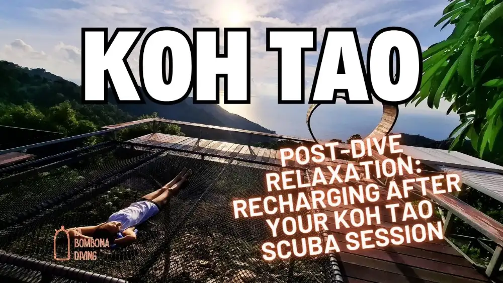 A diver relaxing on a sun lounger on a Koh Tao beach after a dive, turquoise water and longtail boats in the background