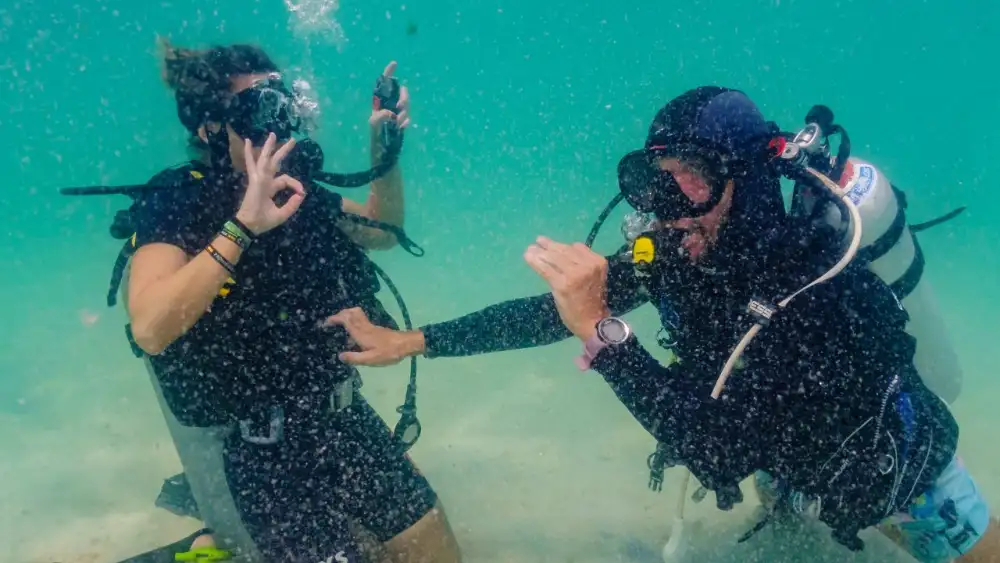 An instructor and student practising skills underwater during a diving certification course on Koh Tao