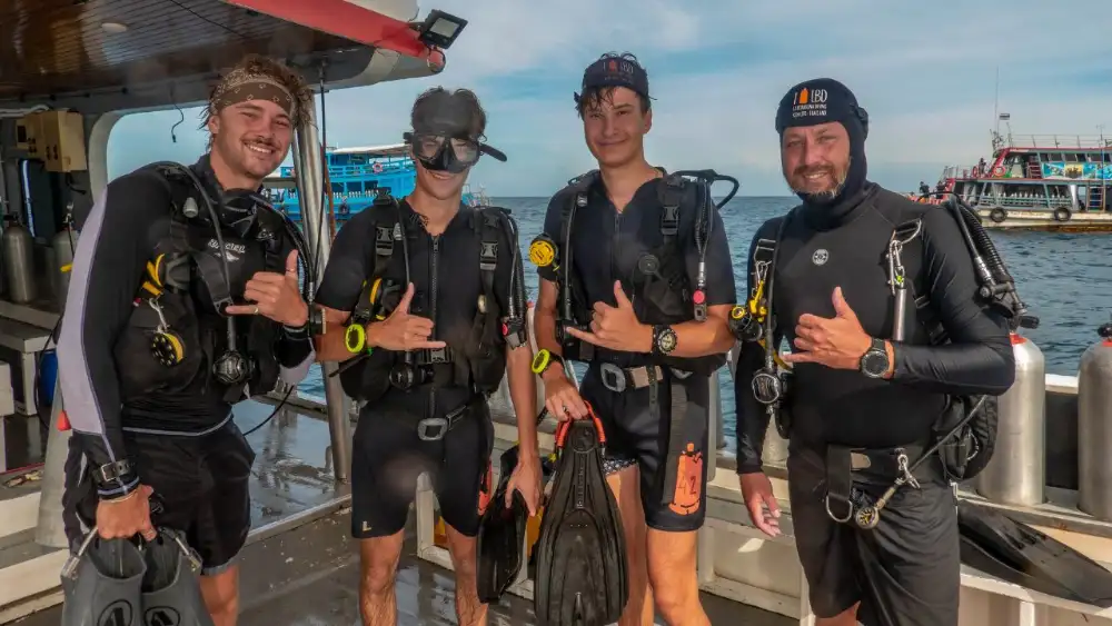 A professional divemaster preparing dive equipment on deck before a dive