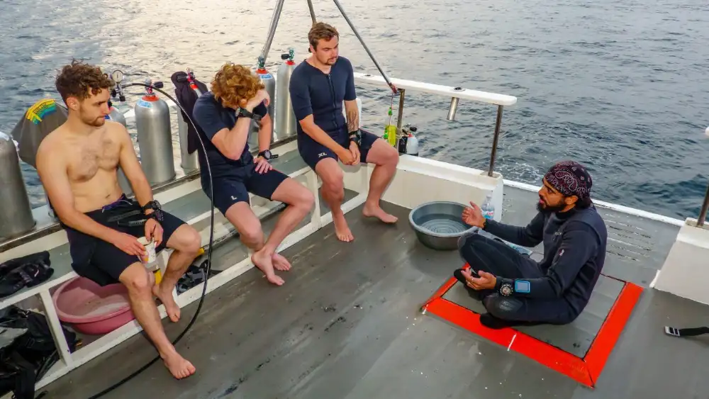 A professional divemaster leading a group of divers along a Koh Tao dive site